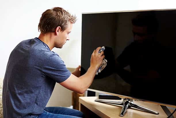 Un homme en train de nettoyer un écran de TV