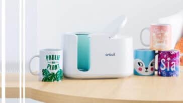 La machine à presse chaud Cricut Mug Press sur une table, avec des mugs personnalisés à côté d'elle