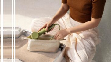 Une femme en train de mettre le Laifen Hair Dryer Mini dans une trousse, prête à être rangée dans une valise de voyage.