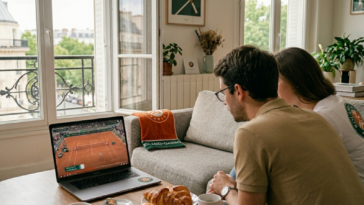 Un couple regarde un match de tennis de Roland-Garros en streaming sur un ordinateur portable dans un appartement parisien.