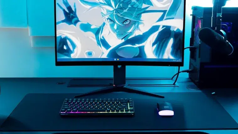 Vue d'ensemble d'une configuration de jeu éclairée en bleu avec un moniteur, un PC et un clavier CHERRY K33 compact.