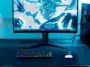 Vue d'ensemble d'une configuration de jeu éclairée en bleu avec un moniteur, un PC et un clavier CHERRY K33 compact.