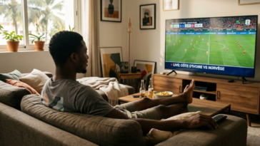 Homme assis confortablement dans son salon, regardant le match de football Côte d'Ivoire VS Norvège à la télévision