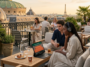 Un couple regarde le tournoi de tennis de Roland-Garros sur une tablette depuis un rooftop à Paris avec vue sur l'Opéra Garnier.
