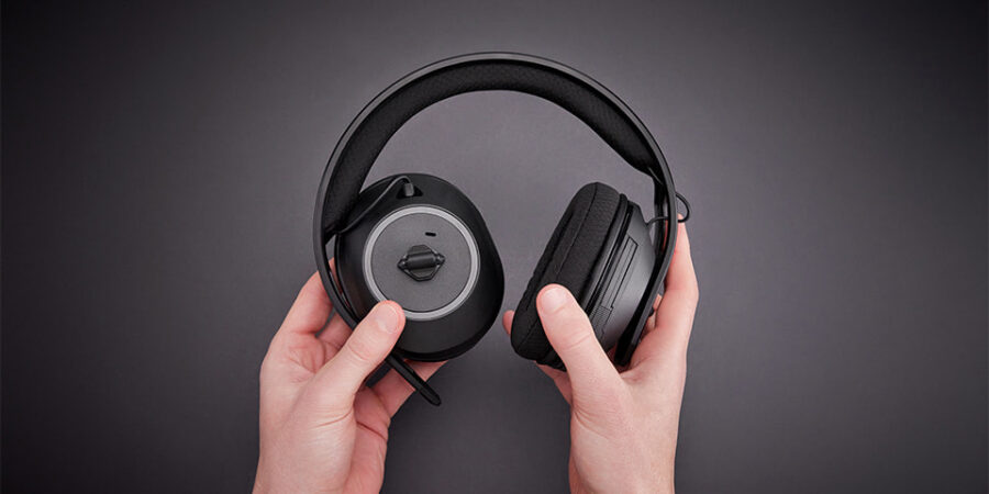 Mains manipulant les oreillettes d'un casque Nacon RIG 600 PRO HS sur un fond gris.