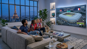 Amis regardant un match de football Norvège vs France de la Coupe du Monde 2026 dans un salon avec vue sur la Tour Eiffel.