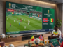 "Couple regardant le match de football Norvège contre Sénégal de la Coupe du Monde 2026 sur un écran géant dans un salon