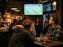 Clients dans un pub sombre regardant un match de football Pays-Bas VS Maroc sur un écran de télévision.