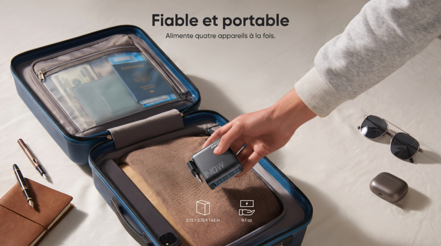 Chargeur Anker Zolo 140W tenu à la main et rangé dans une valise de voyage ouverte.