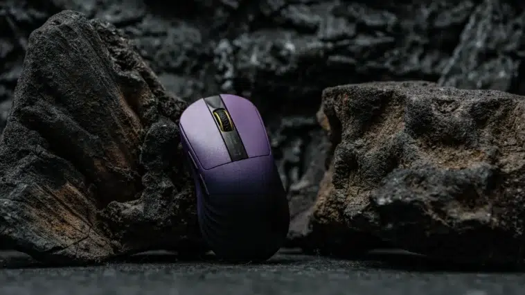 Souris gaming Epomaker Carbonis violette debout entre des rochers de lave noirs et texturés, éclairée de manière dramatique.