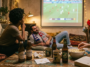 Amis regardant un match de football entre les États-Unis et la Belgique projeté sur un grand écran dans un salon chaleureux.
