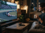 Femme regardant le Grand Prix de Formule 1 de Hongrie sur grand écran dans un salon chaleureux.