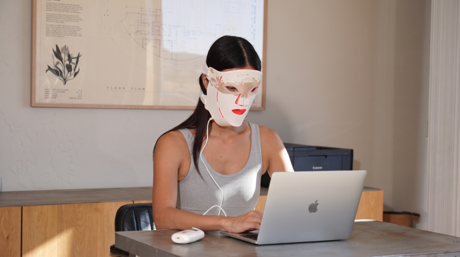 Une femme utilise le masque LED Renpho Artemis en travaillant sur son ordinateur portable.