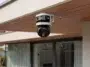 Photo de la caméra de surveillance multi-objectifs Reolink OMVI 3i WiFi installée sous l'auvent d'une maison moderne.
