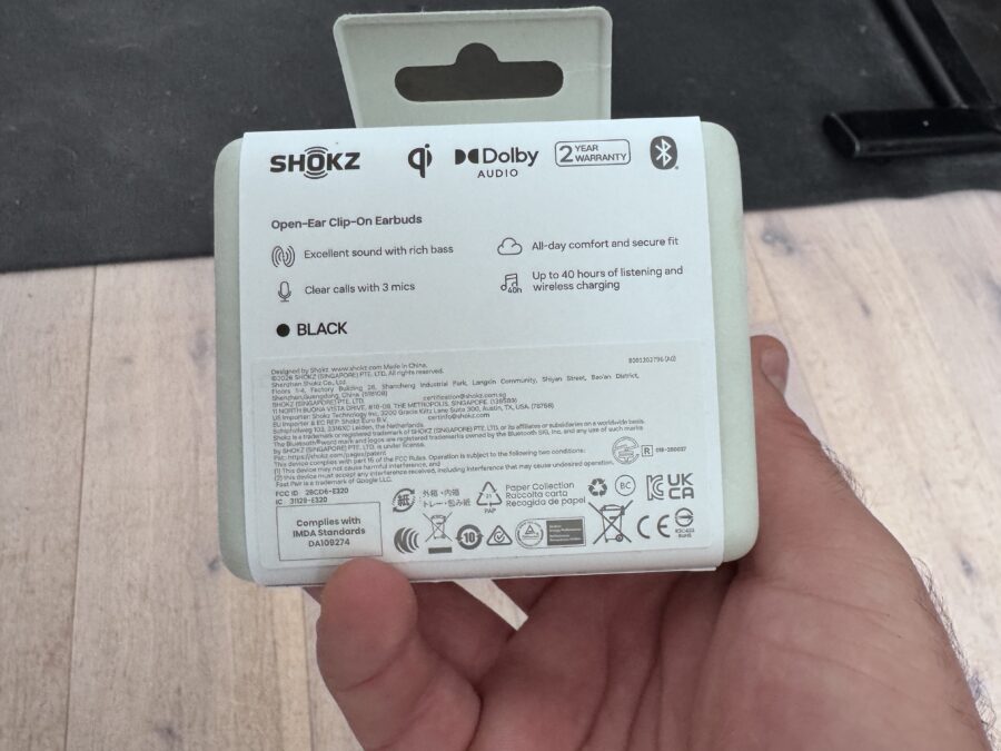 Le dos de la boîte d'emballage des écouteurs Shokz OpenDots 2 tenu par une main.