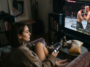 Femme regardant le combat UFC Fight Night Ankalaev vs Guskov à la télévision dans un salon cosy.