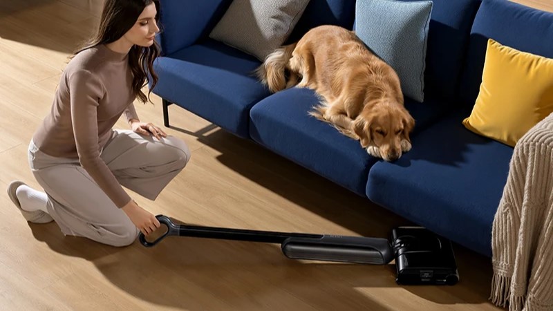 Une femme met à plat le JONR H2 pour passer l'aspirateur sous le canapé.