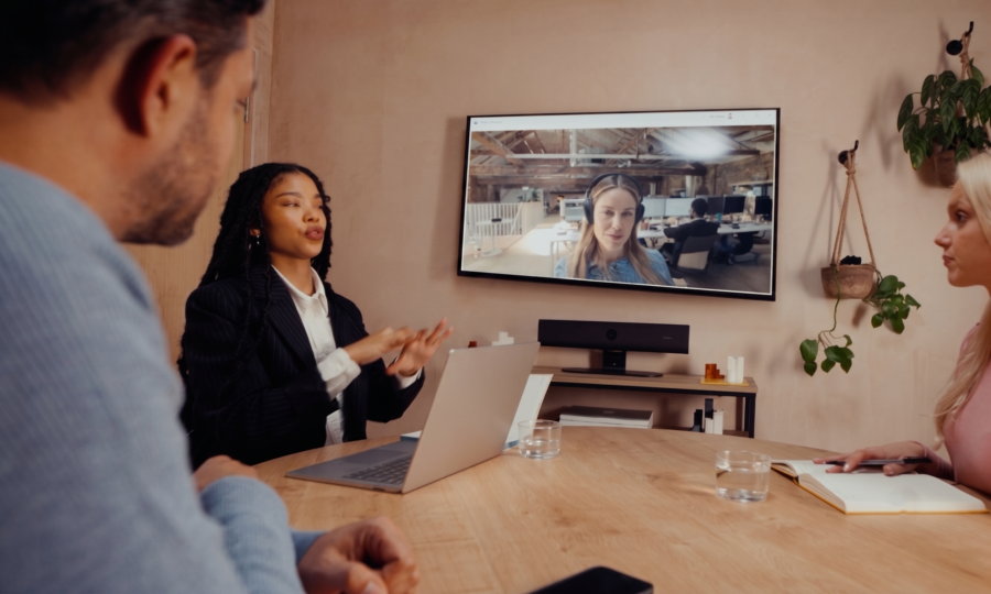 Barre de visioconférence PanaCast U30 installée sous l'écran mural lors d'une réunion de bureau moderne.