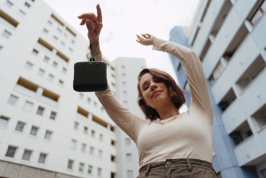 Une femme qui présente la Teufel BOOMSTER GO suspendue à sa dragonne.