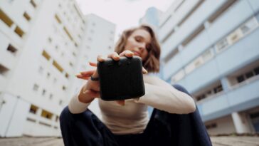 Une femme tient dans sa main la Teufel BOOMSTER GO pour mettre l'enceinte en avant.
