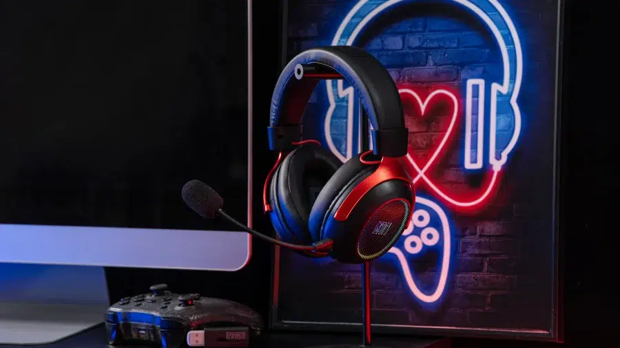 Le casque EPOMAKER GX1 placé à côté d'un moniteur et d'une manette Xbox.