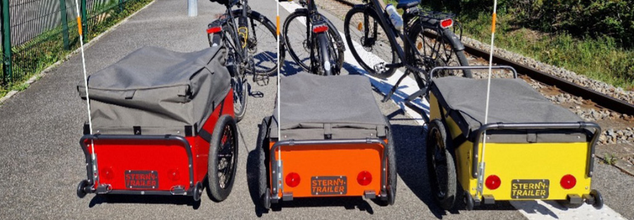 Des remorques STERNYTRAILER derrière des vélos sur une piste cyclable.