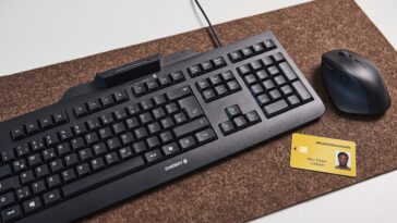Le clavier CHERRY SMART BOARD 1150 posé sur un bureau à côté d'une souris et d'une carte à puce.