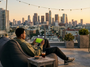 Jeune homme qui regarde du football en streaming sur tablette depuis un rooftop.